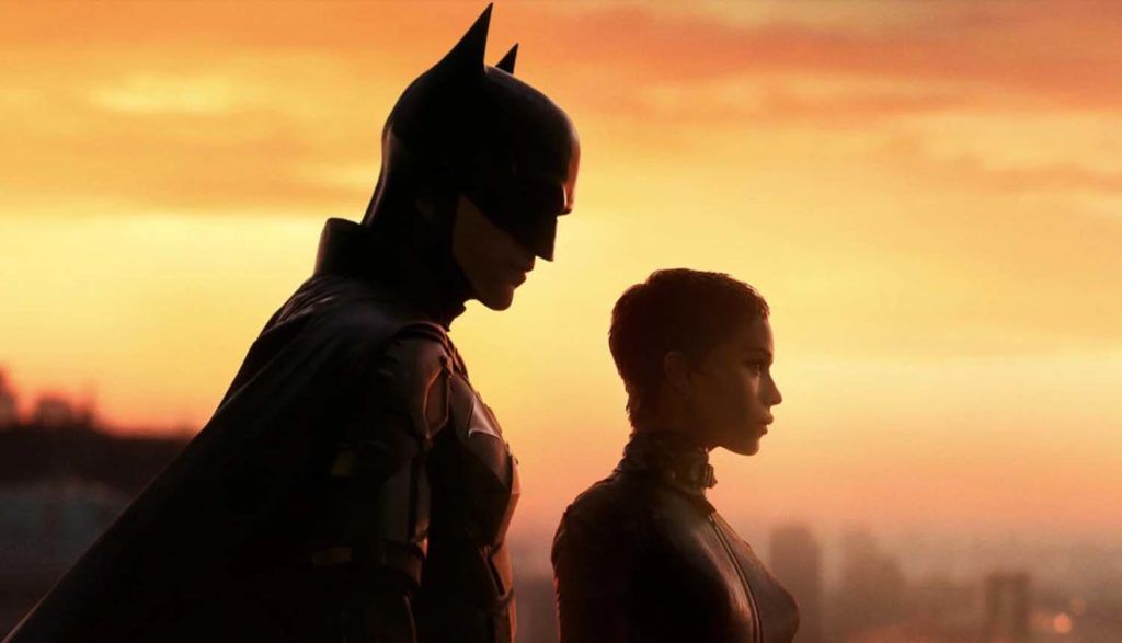 Against an orange sunset, Zoë Kravitz as Selina Kyle and Robert Pattinson as Batman are overlooking Gotham City. Against an orange sunset, Zoë Kravitz as Selina Kyle and Robert Pattinson as Batman are overlooking Gotham City.